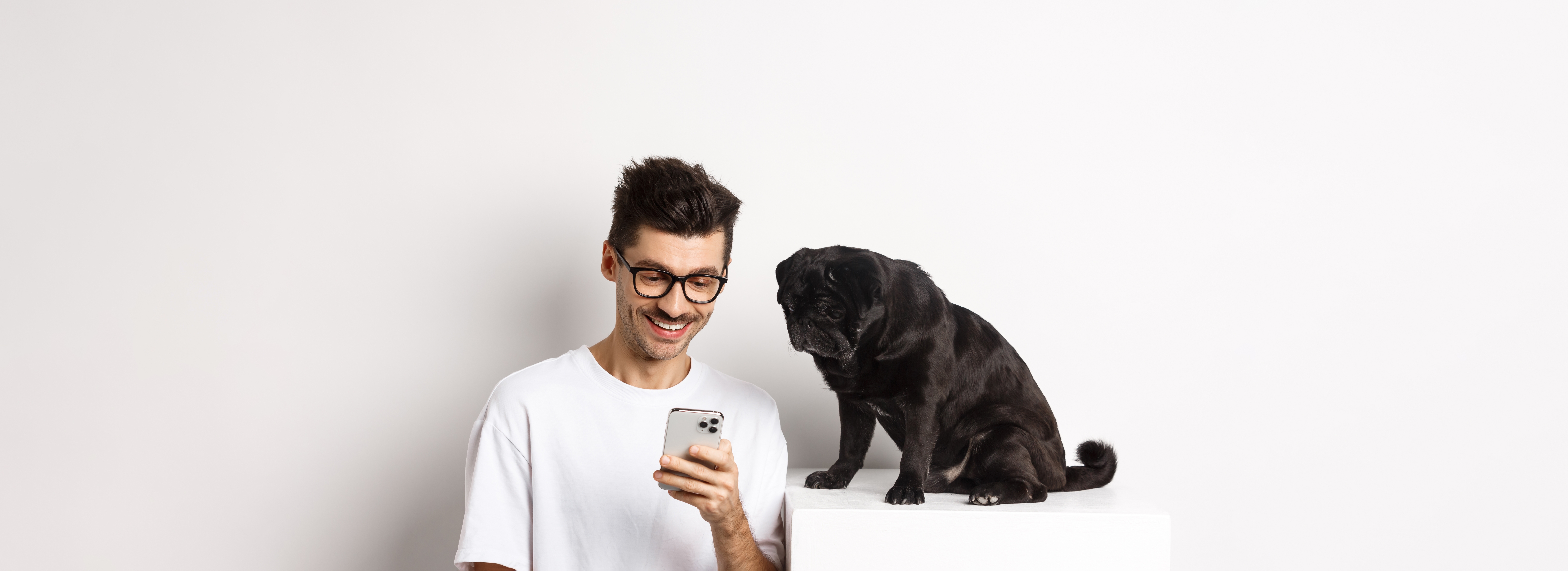 Smiling,Young,Man,Using,Smartphone,And,Sitting,Near,Dog.,Pug